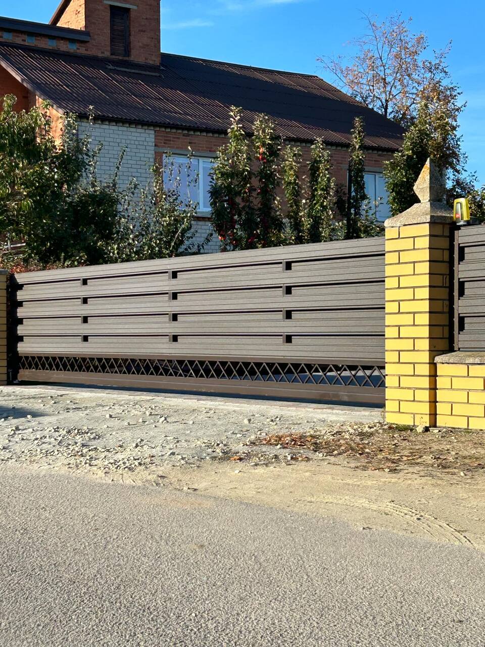 Gjerde med horisontale metallspiler mellom murte pilarer
