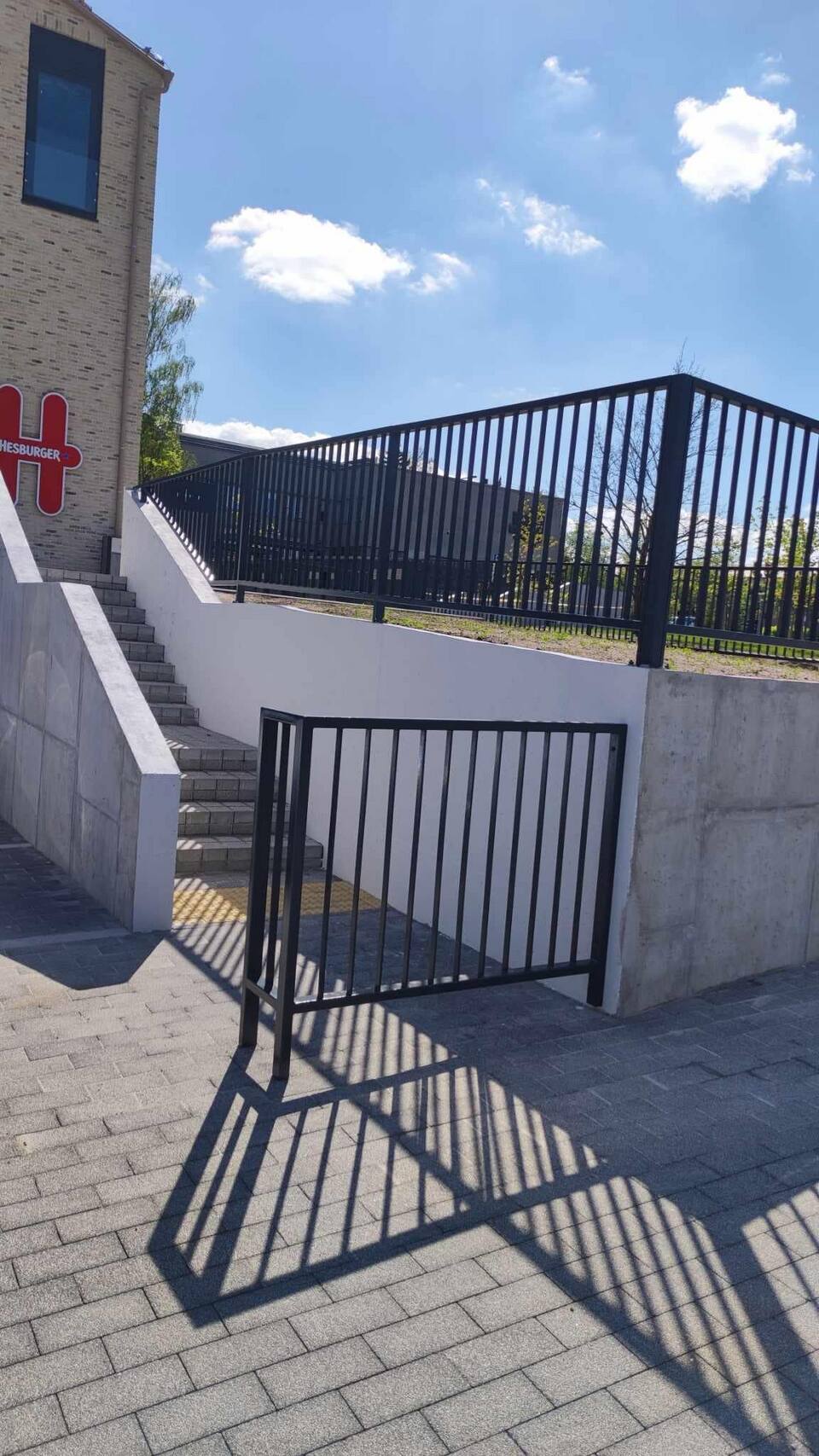Port og gjerde i mørkt stål på belagt gårdsplass