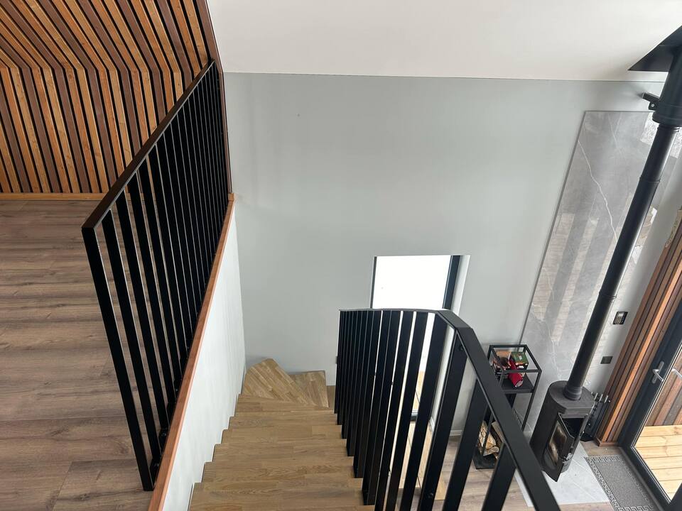 Innvendig rekkverk i sort stål mot vegg med trespiler
